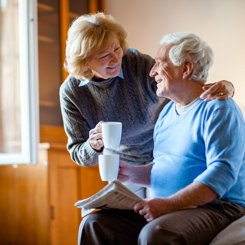 Woman handing a water glass to a senior man with dementia