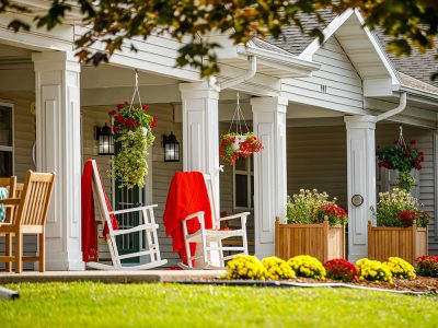 Covered porch with planters and rocking chairs.